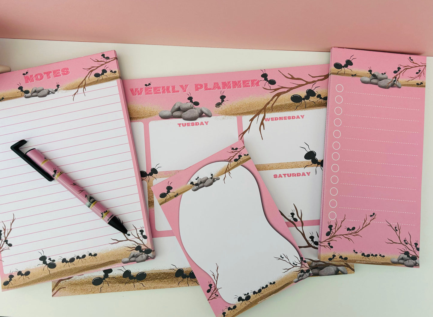 Stationary set with Memo pad, to-do list, weekly agenda, ballpoint pen A5 Lined Note Pad Marching Pink by Pink Themed 50 Pages 120gsm, flat on white table with Ants designed on pages