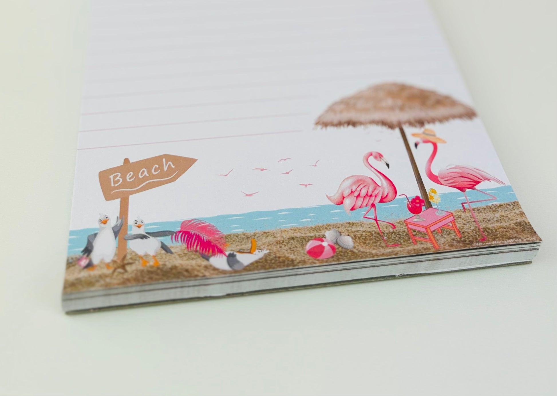 A5 Lined Note Pad Pink by the Ocean Themed 50 Pages 120gsm, focus on footer with flamingos, beach, sand, seagulls 