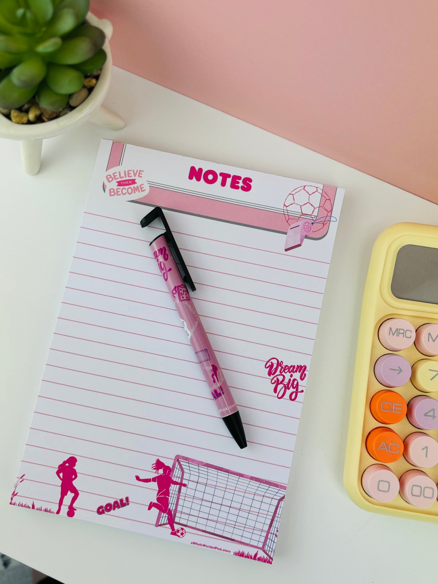 A5 Lined Note Pad A League Of Pink Themed 50 Pages, A League of Pink themed Ballpoint pen, and Yellow calculator, from above